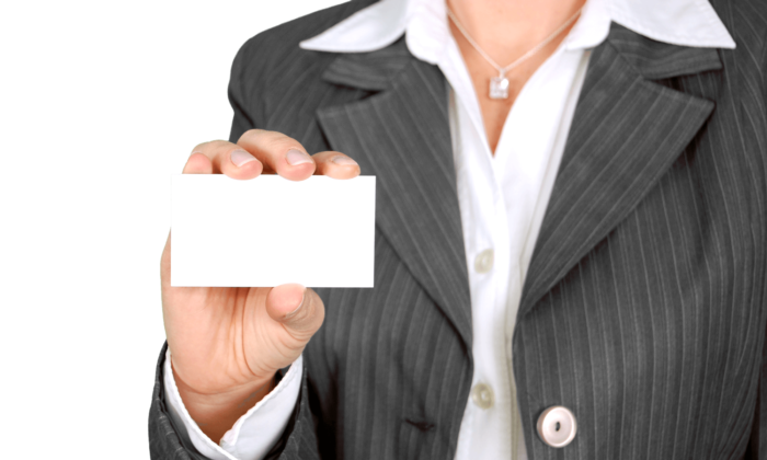 Woman in a pant suit with a blank business card presented in front of her.