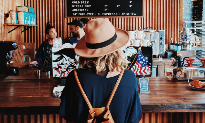 Woman with a hat waiting at a coffee shop counter looking for customer lifetime value